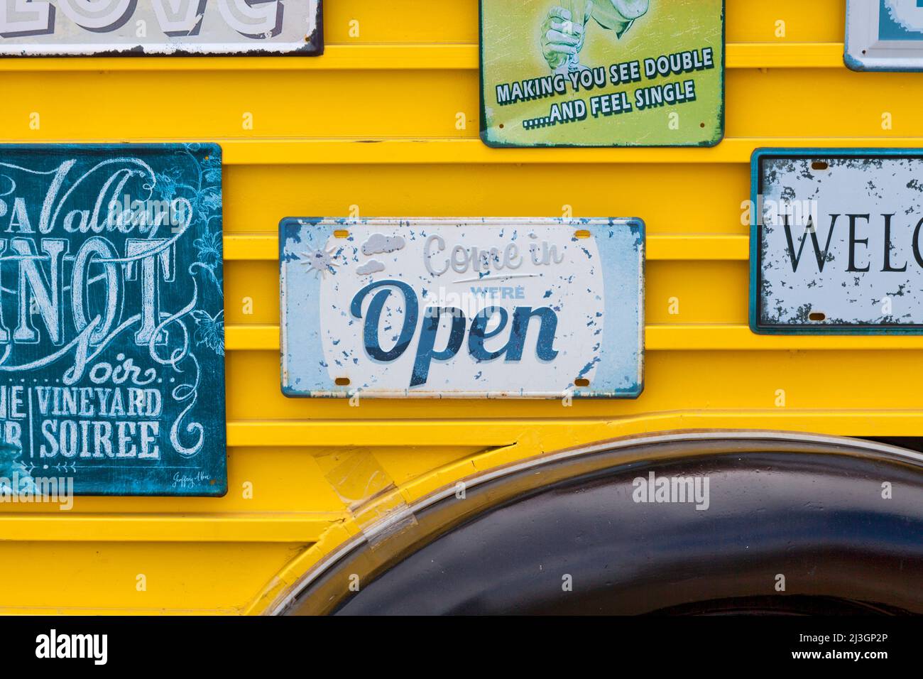 Offenes Schild, umgeben von einem anderen alten Modeschild an der Seite eines Food Trucks. Stockfoto