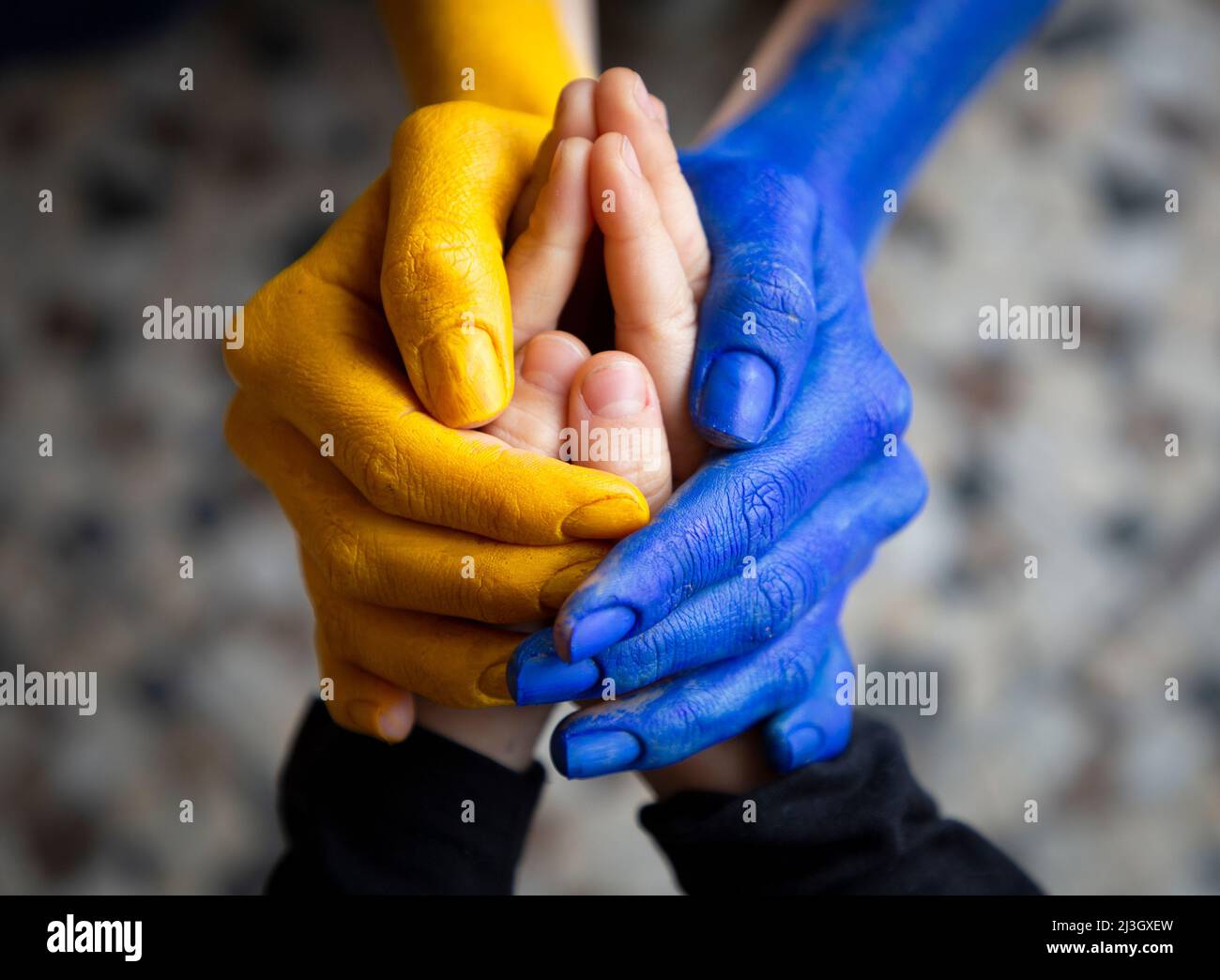 Weibliche Hände in gelben und blauen Farben der ukrainischen Flagge gemalt halten kleine Kinderhände. Familie zusammen, Pflege. Schutz der psychischen Gesundheit des Kindes Stockfoto