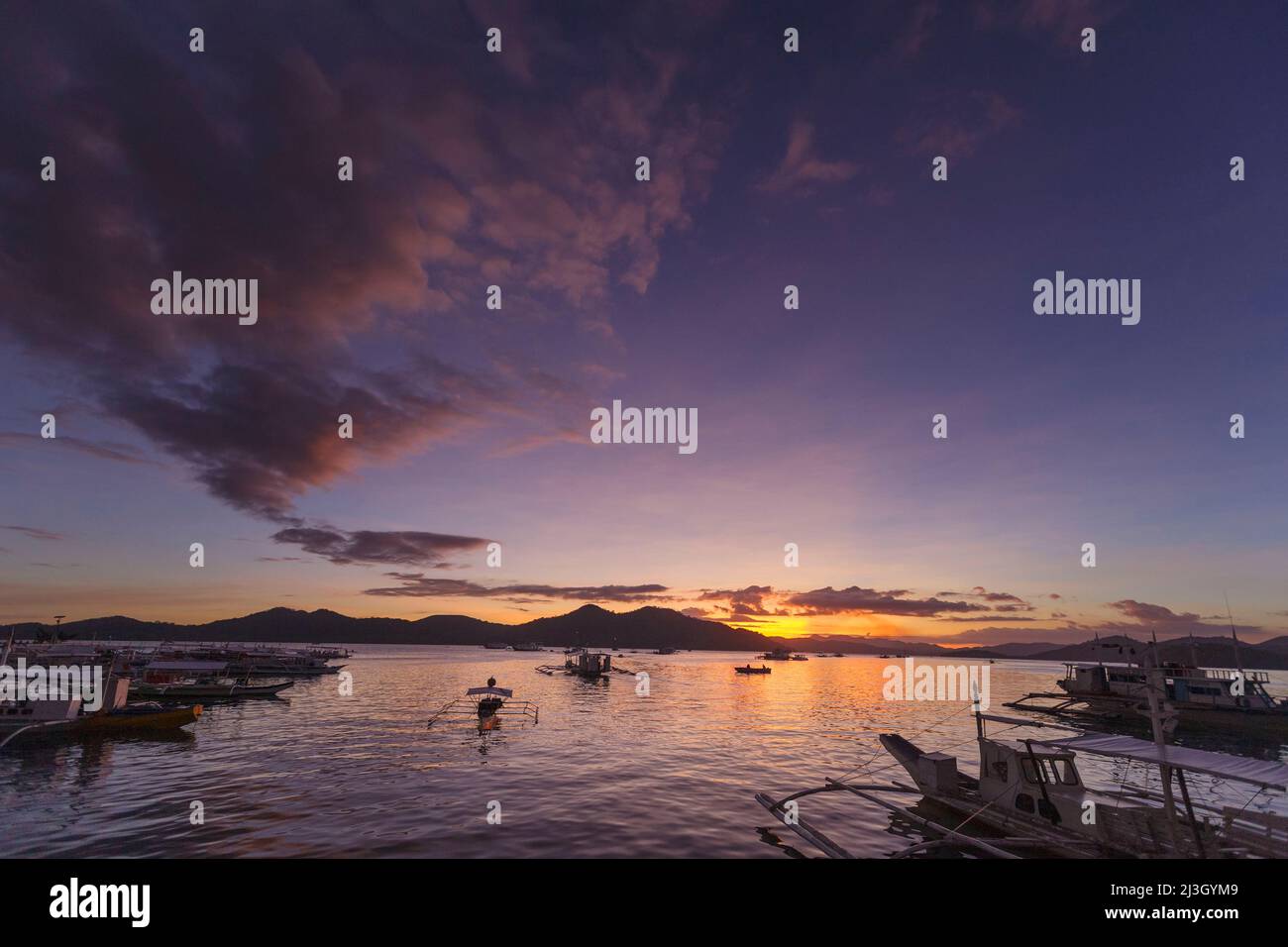 Philippinen, Palawan, Calamians-Archipel, Coron Town, Sonnenuntergang über dem Meer und Kanus gegen das Licht Stockfoto