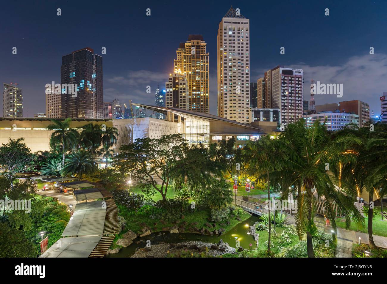 Philippinen, Metro Manila, Makati District, Blick auf die Greenbelt Mall bei Nacht und beleuchtete Wolkenkratzer im Hintergrund Stockfoto