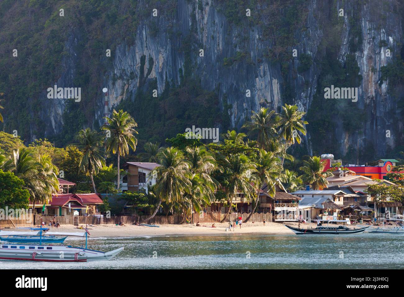 Philippinen, Palawan, El Nido, Touristenstrand, Hotels, Kokospalmen, Klippen und Kanus Stockfoto