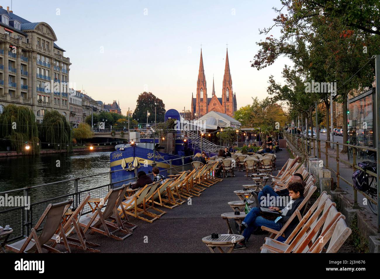 Frankreich, Bas-Rhin, Straßburg, Altstadt, die von der UNESCO zum Weltkulturerbe erklärt wurde, Cafés Boote auf dem Quai des Batelers am Ufer der Ill und Saint-Paul Kirche im Hintergrund Frankreich, Bas-Rhin (67), Straßburg, vieille ville classée au Patrimoine Mondial de l'UNESCO, Bistrots péniches le long du quai des Pêcheurs au Bord de l'ill avec église Saint-Paul en arrière Plan Stockfoto