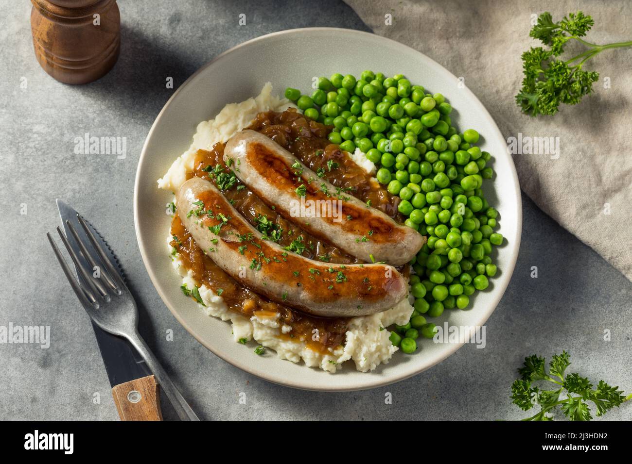 Hausgemachte britische Bangers und Maische mit Zwiebelsoße Stockfoto