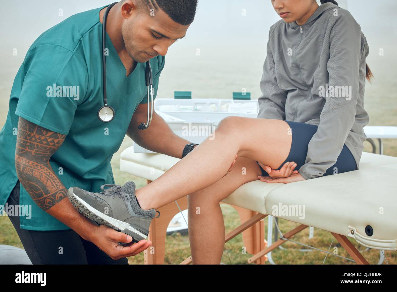 Alle Schmerzen. Zugeschnittene Aufnahme eines hübschen jungen männlichen Physiotherapeuten, der draußen an einer weiblichen Patientin arbeitet. Stockfoto