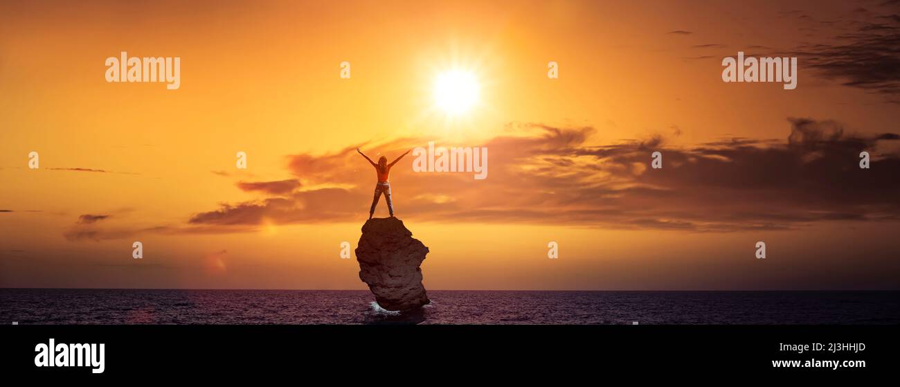 Frau auf einem Felsen im Meer, Arme ausgestreckt Stockfoto