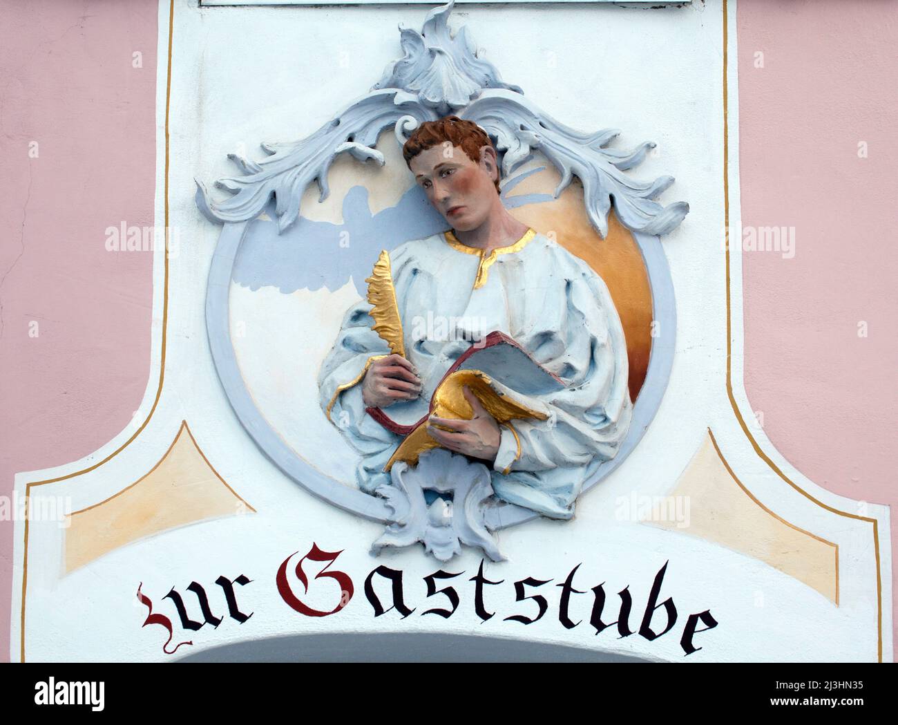 Johannes der Evangelist, auch in der kirchlichen Tradition als Johannes der Evangelist oder Johannes vom (lateinischen) Tor bekannt, ist der Hauptautor des Johannesevangeliums, Wandrelief an der Hausfassade im oberbayerischen Mittenwald Stockfoto