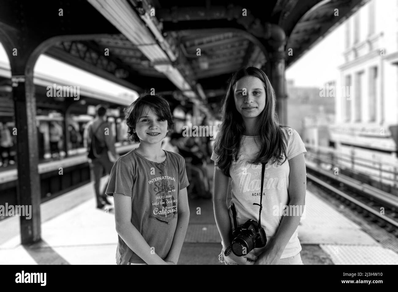 Myrtle AV, New York City, NY, USA, 14 Jahre altes kaukasisches Teenager-Mädchen und 12 Jahre altes kaukasisches Teenager-Mädchen – beide mit braunen Haaren und sommerlichem Styling warten an einer U-Bahn-Station in Brooklyn auf die U-Bahn Stockfoto