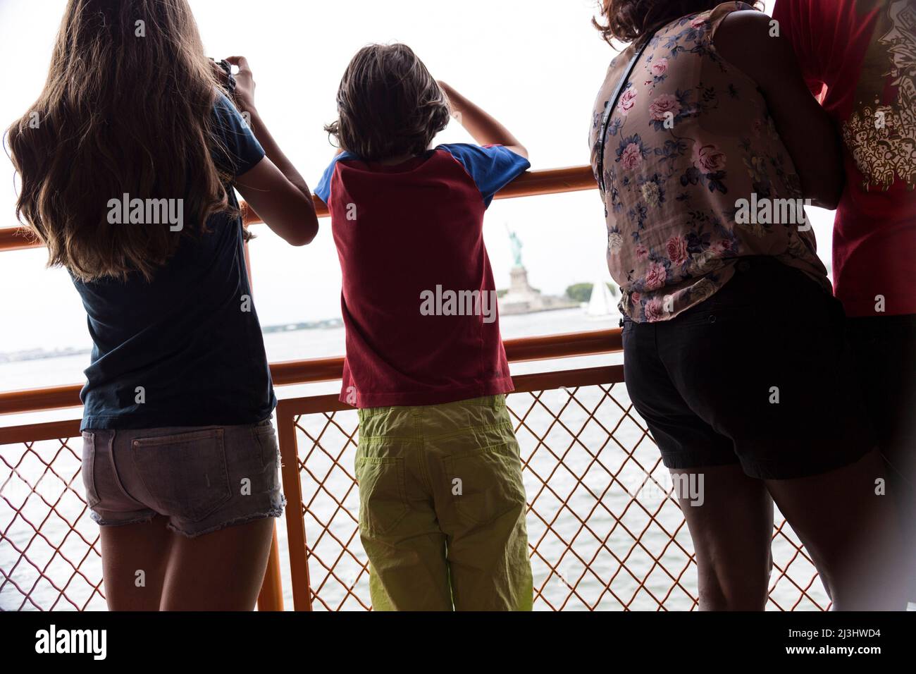 New York City, NY, USA, 14 Jahre altes kaukasisches Teenager-Mädchen und 12 Jahre altes kaukasisches Teenager-Mädchen – beide mit braunen Haaren und sommerlichem Styling auf der staten Island Ferry. Freiheitsstatue dahinter Stockfoto