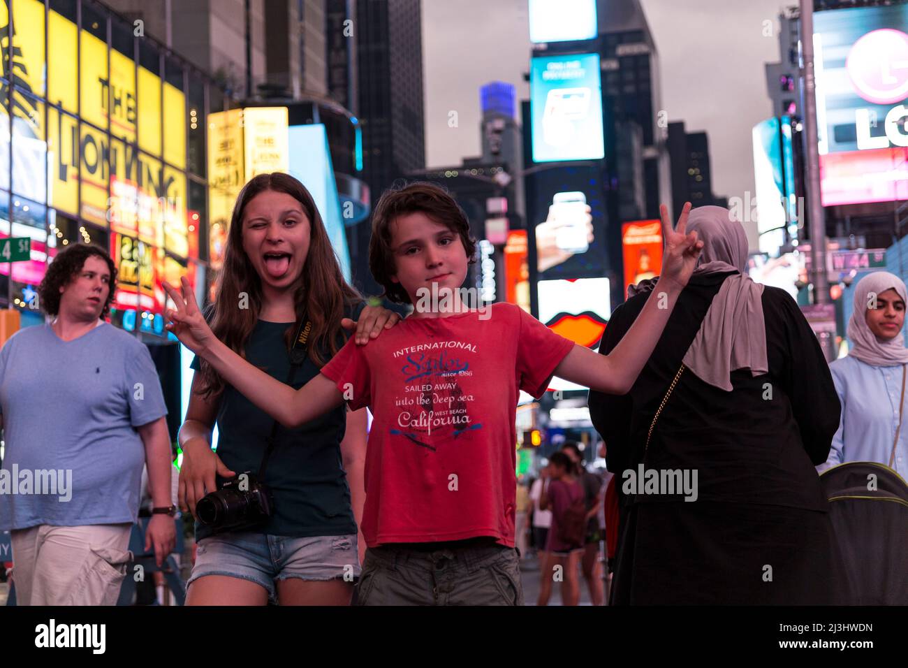 Theatre District, New York City, NY, USA, 14 Jahre altes kaukasisches Teenager-Mädchen und 12 Jahre altes kaukasisches Teenager-Mädchen – beide mit braunen Haaren und sommerlichem Styling posieren auf dem Times Square Stockfoto