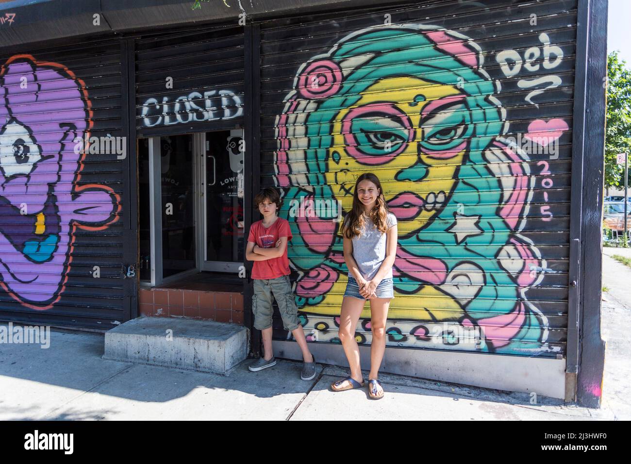 Bushwick, New York City, NY, USA, 14 Jahre altes kaukasisches Teenager-Mädchen und 12 Jahre altes kaukasisches Teenager-Mädchen – beide mit braunen Haaren und sommerlichem Styling vor einem Graffiti Stockfoto