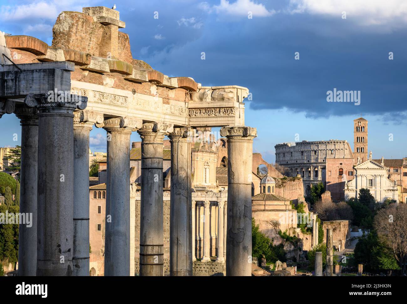 Vom Kapitol aus blickt man auf das Forum Romanum, mit dem Saturn-Tempel im Vordergrund und dem Kolosseum in der Ferne, Rom, Italien. Stockfoto