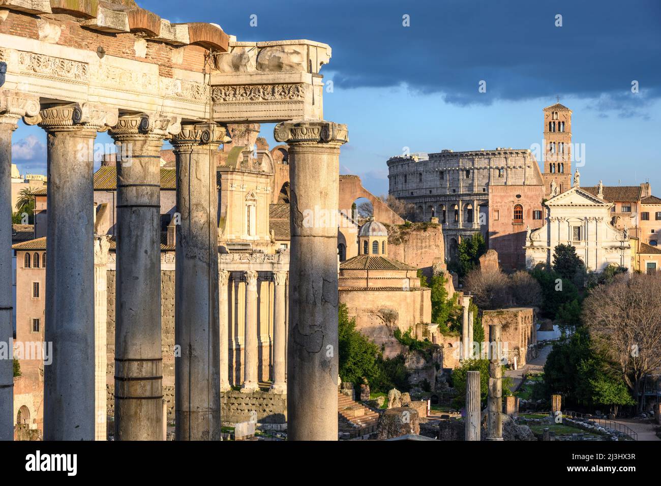 Vom Kapitol aus blickt man auf das Forum Romanum, mit dem Saturn-Tempel im Vordergrund und dem Kolosseum in der Ferne, Rom, Italien. Stockfoto