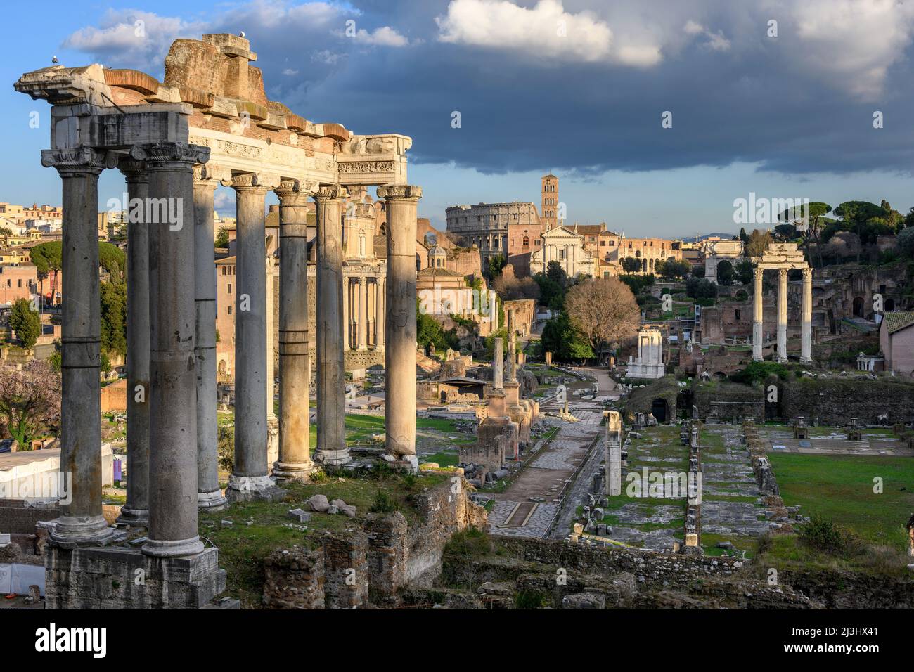 Vom Kapitol aus blickt man auf das Forum Romanum, mit dem Saturn-Tempel im Vordergrund und dem Kolosseum in der Ferne, Rom, Italien. Stockfoto