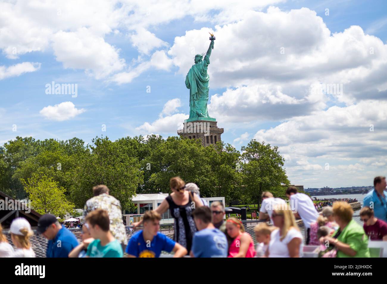 LIBERTY ISLAND, NYC, NEW YORK, USA, ein unerwarteter Blick auf die weltberühmte Freiheitsstatue in New York City. Gefangen vor einem dramatischen Himmel. Stockfoto
