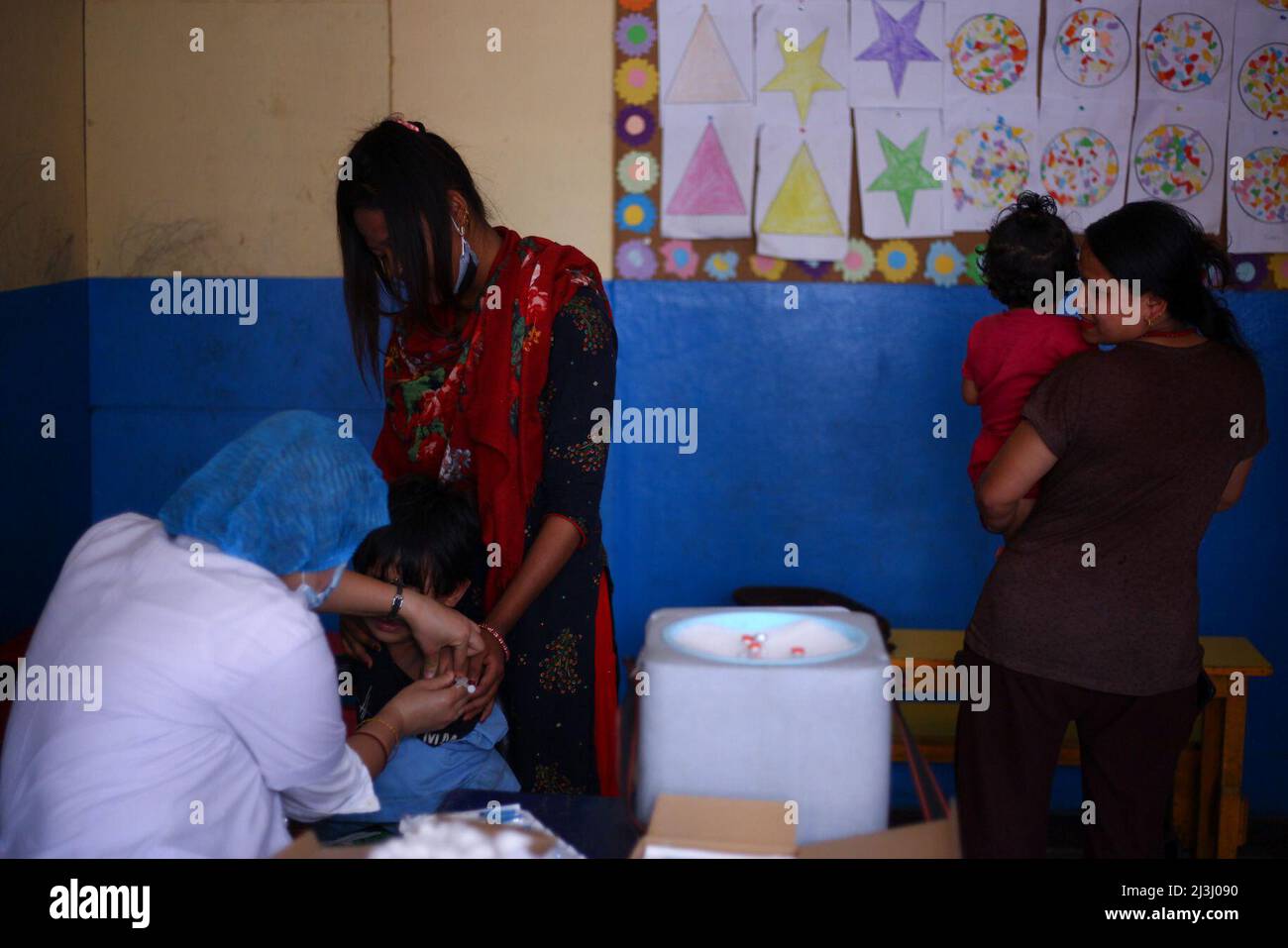 Kathmandu, Nepal. 08. April 2022. Am 8. April 2022 in Kathmandu, Nepal. Frauen, die ihre Tochter tragen, warten auf den Typhusimpfstoff und sehen zu, wie ein Junge während des Impfcampignings geimpft wird. Im Rahmen dieser Kampagne werden alle Kinder zwischen 15 Monaten und 15 Jahren geimpft. Der Impfstoff ist frei, sicher und wirksam und wird dem Gesundheitsministerium und der Bevölkerung zugesichert. (Foto: Abhishek Maharjan/Sipa USA) Quelle: SIPA USA/Alamy Live News Stockfoto