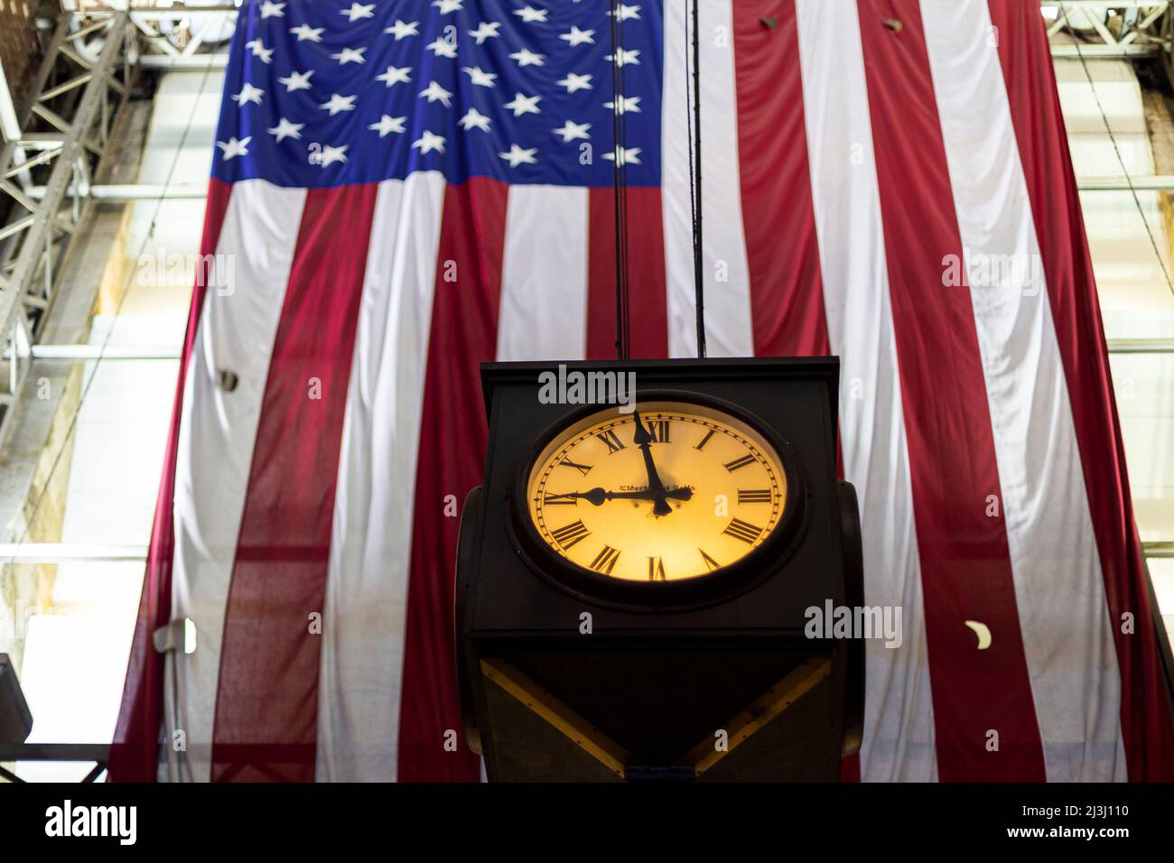 W 34 ST/7 AV, New York City, NY, USA, die amerikanische Flagge hinter einer Uhr Stockfoto