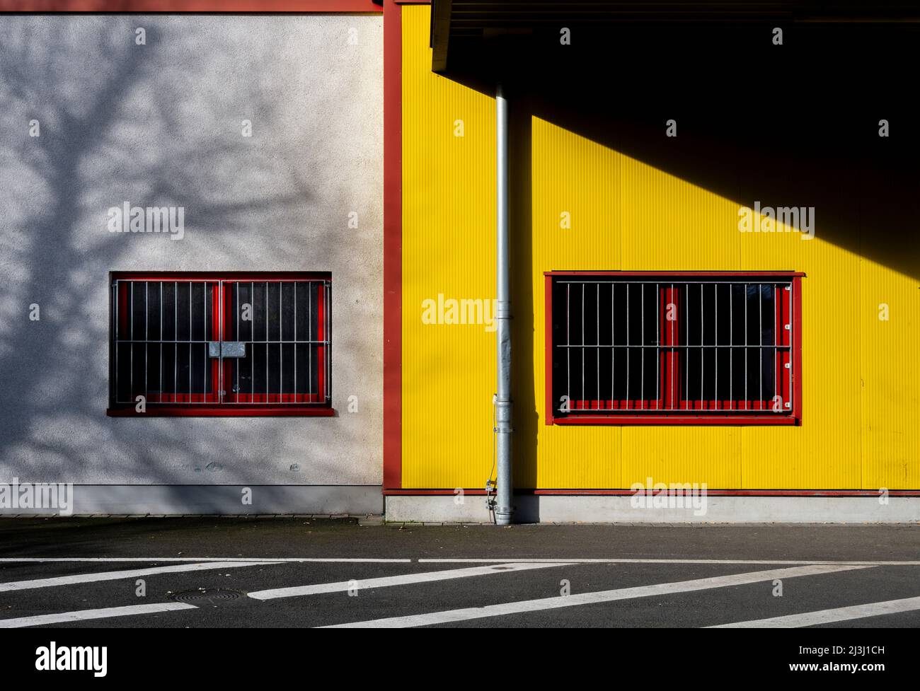Gelbes Lagerhaus, roter Rahmen, Fenster mit Sperrinenabsperrung, Schatten, Stockfoto
