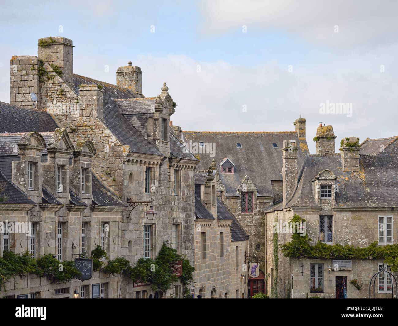 Fassaden von Häusern im Dorf Locronan im Departement Finistère in der Bretagne. Die Häuser wurden aus Granit gebaut und stammen aus dem 17.. Jahrhundert. Locronans historische Kulisse ist in vielen Film- und Fernsehproduktionen zu sehen. Locronan ist ein sehr beliebtes Ausflugsziel. Stockfoto