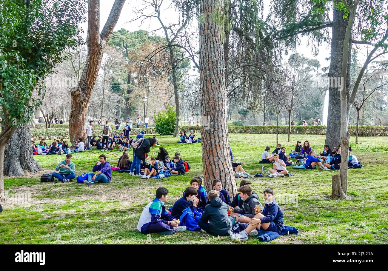 Jugendliche Kinder sitzen auf dem Boden im El Retiro Park, Madrid, Spanien Stockfoto