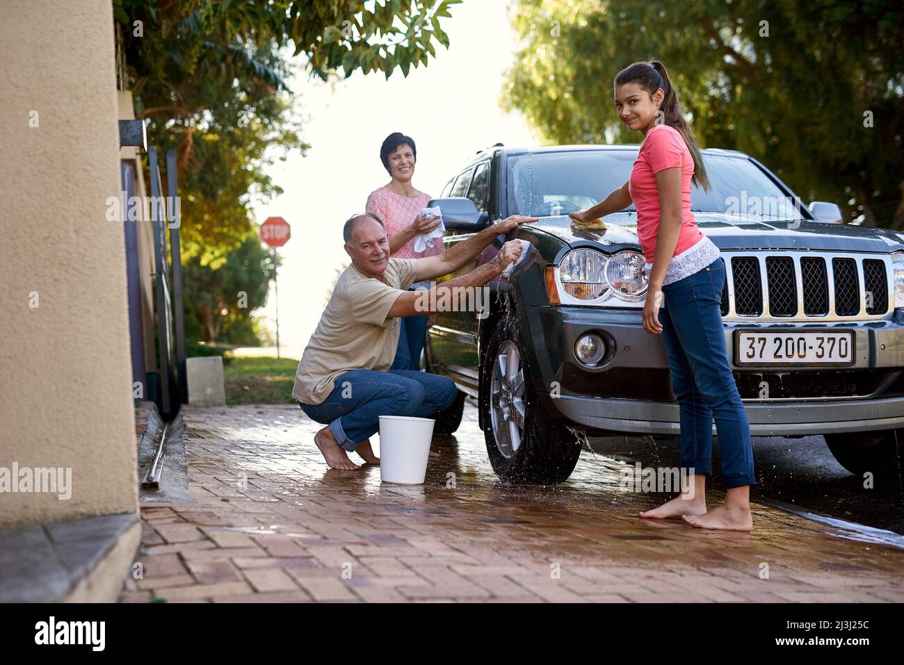 Bindungszeit für die Familie. Porträt einer Familie, die draußen ein Auto gemeinsam wäscht. Stockfoto