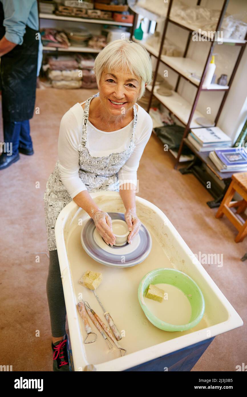 Eine neue Fähigkeit zu erlernen macht so viel Spaß. Aufnahme einer älteren Frau, die in einer Werkstatt einen Keramiktopf macht. Stockfoto