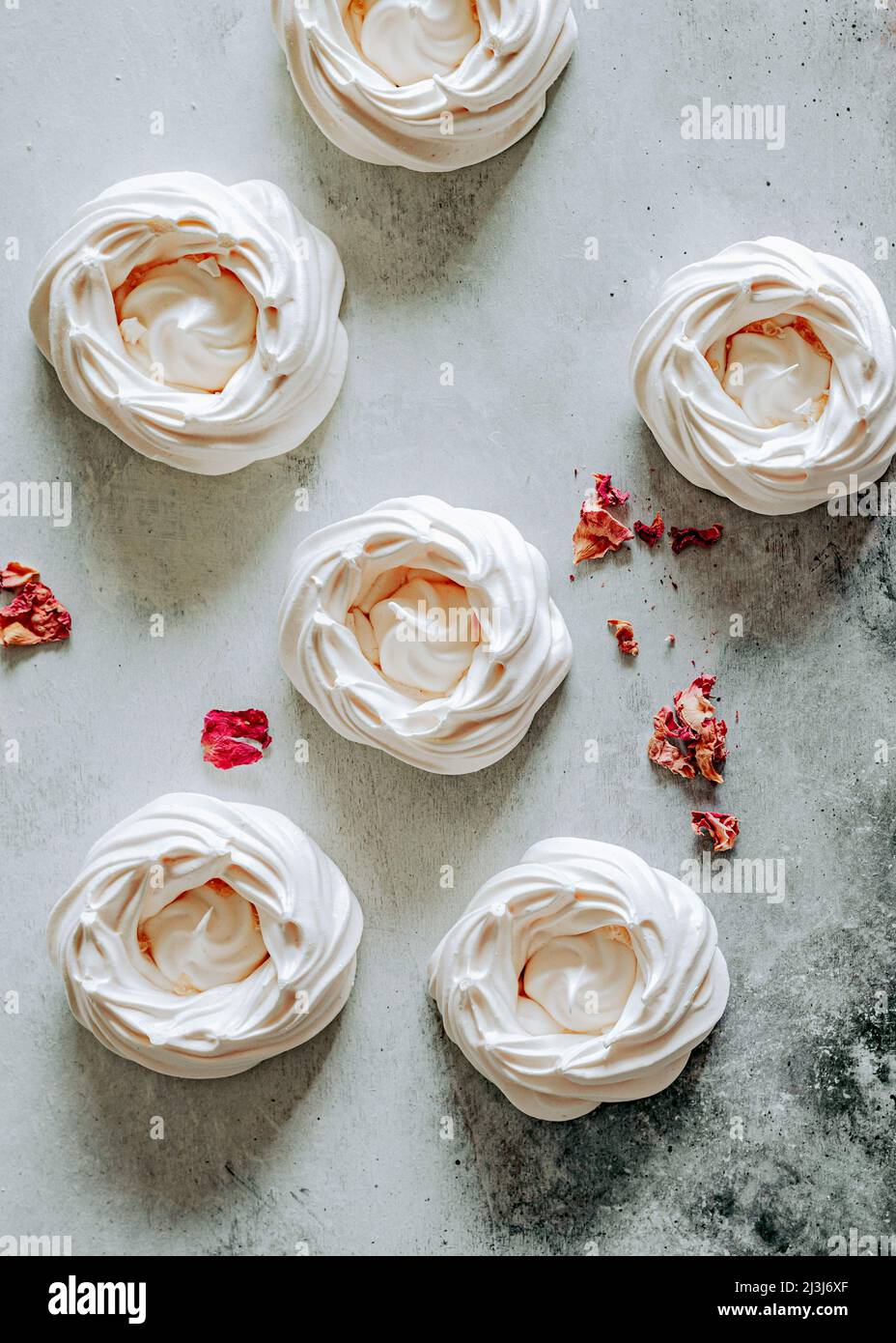 Leere Meringue-Schalen mit Rosenblättern Stockfoto