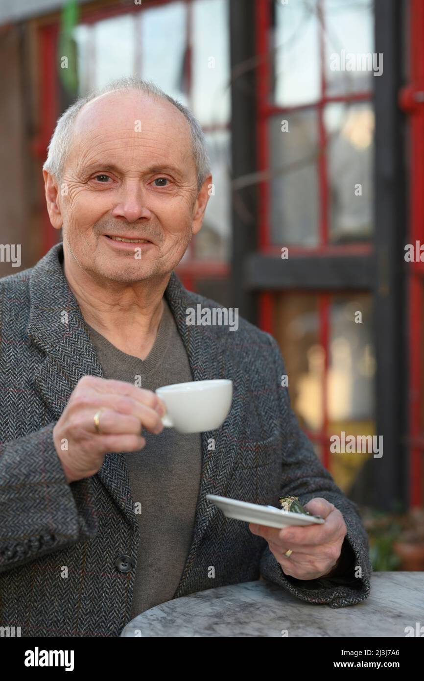 Porträt eines lächelnden grauhaarigen Mannes, der im Garten steht und Kaffee trinkt Stockfoto