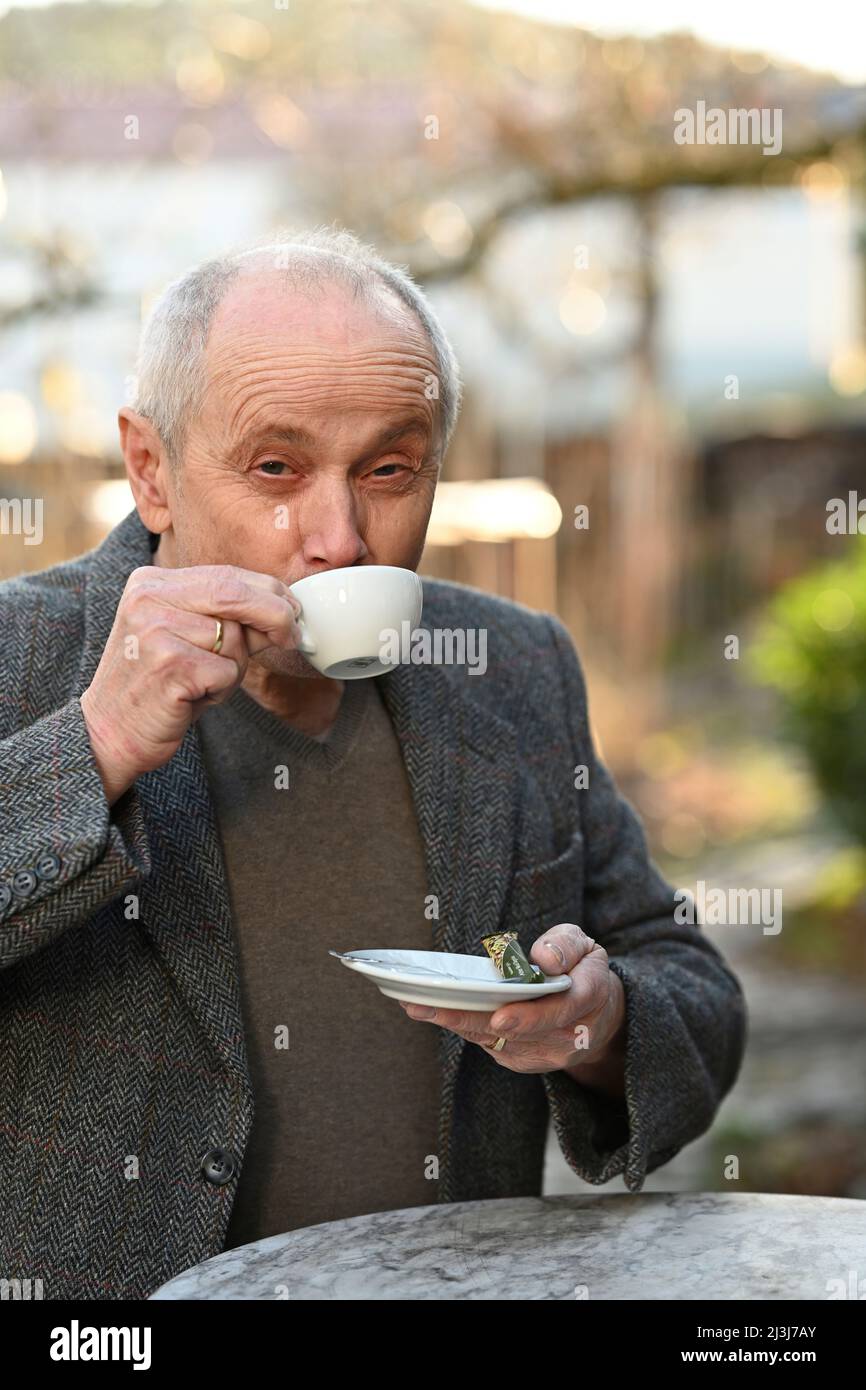 Porträt eines lächelnden grauhaarigen Mannes, der im Garten steht und Kaffee trinkt Stockfoto