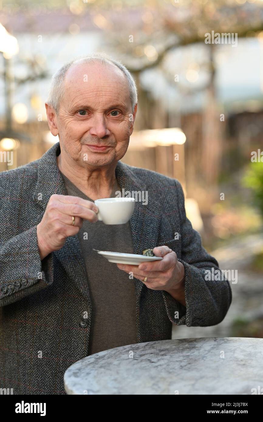 Porträt eines lächelnden grauhaarigen Mannes, der im Garten steht und Kaffee trinkt Stockfoto