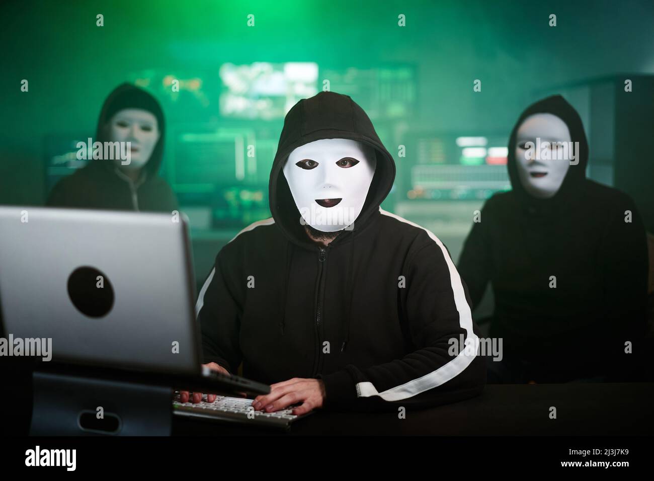 Maskierter Hacker nutzt Computer zur Organisation massiver Angriffe auf Datenschutzverletzungen auf Unternehmensservern. Sie befinden sich in der unterirdischen geheimen Lage, umgeben von Stockfoto