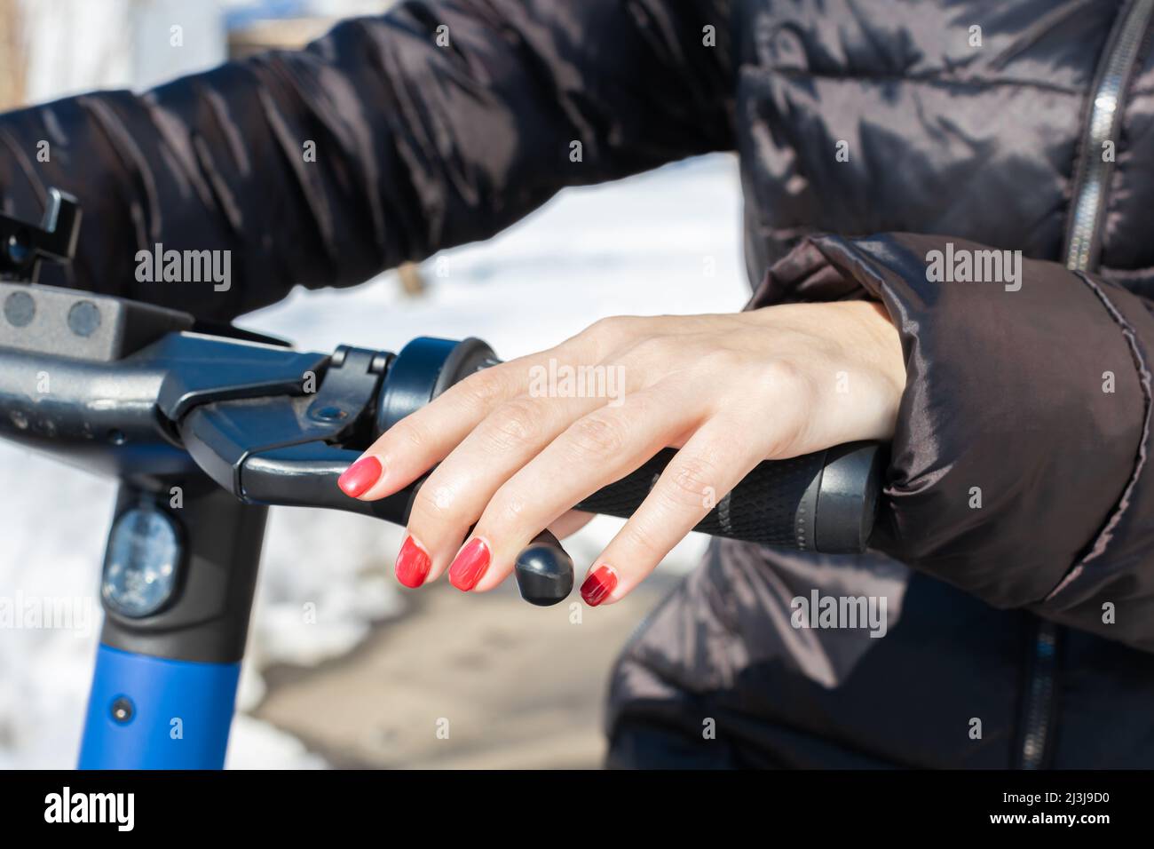 Eine Frauenhand drückt den Gasgriff und die Bremse des Rollers. Hochwertige Fotos Stockfoto