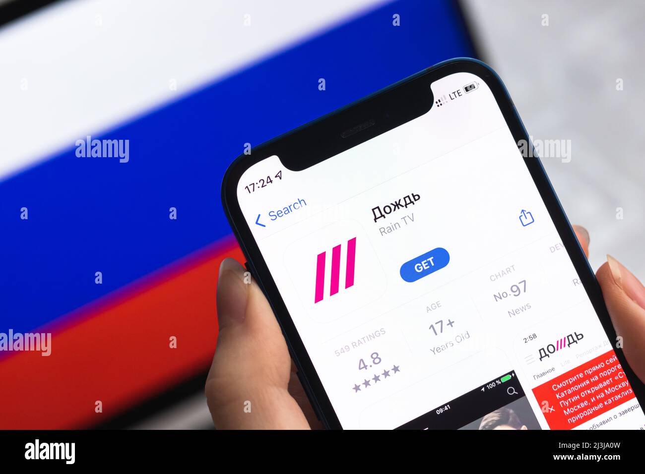 Poltava, Ukraine - 8. April 2022: TV Rain App, Russland Flagge Hintergrund. Blockierte News-Anwendung in der Russischen Föderation, Handy mit Symbol Nahaufnahme Stockfoto