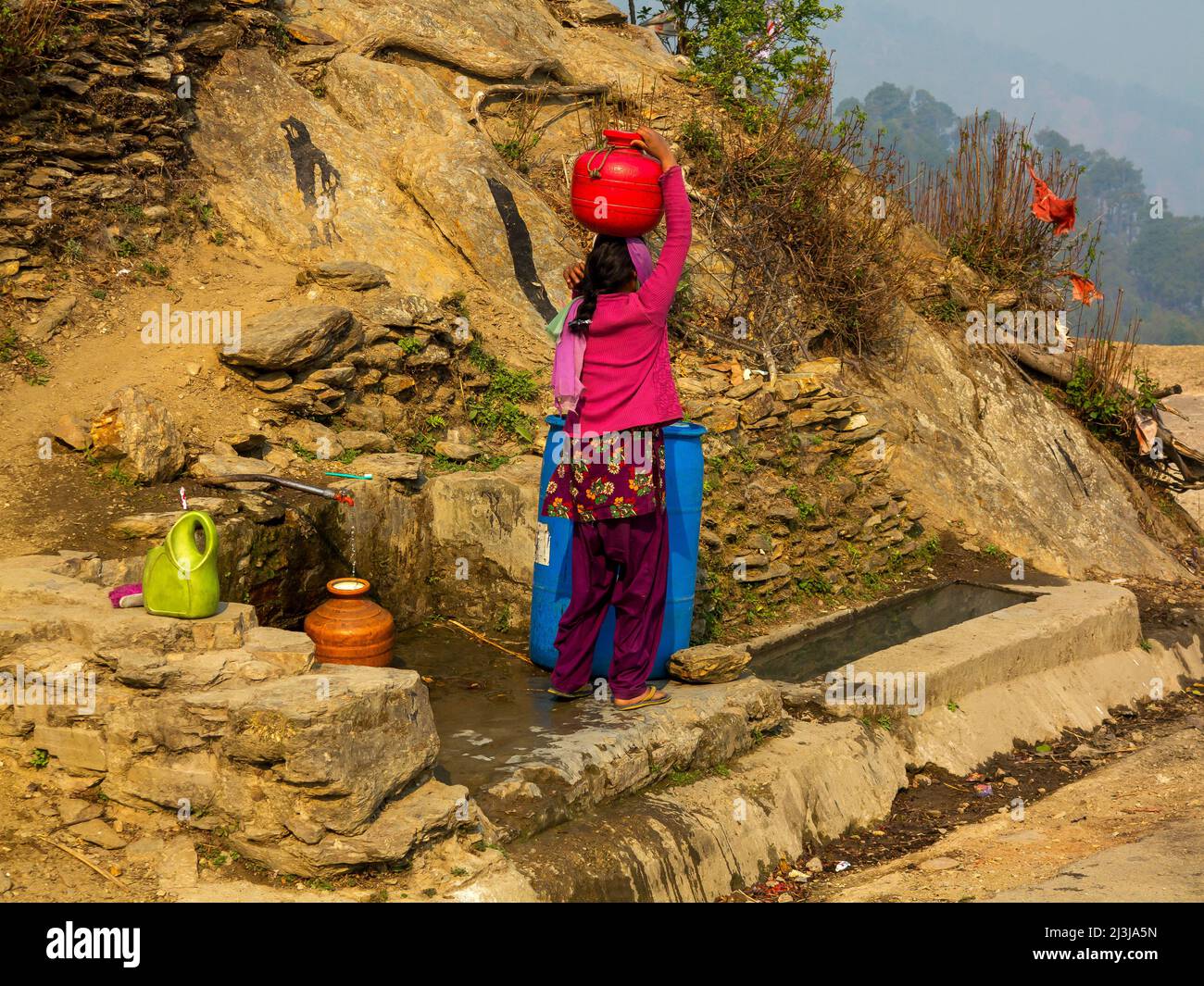 Indische Frau, die Wasser an einer Quelle im Dorf Tulla Kote, Region Kallas des, Uttarakhand, Indien sammelt Stockfoto