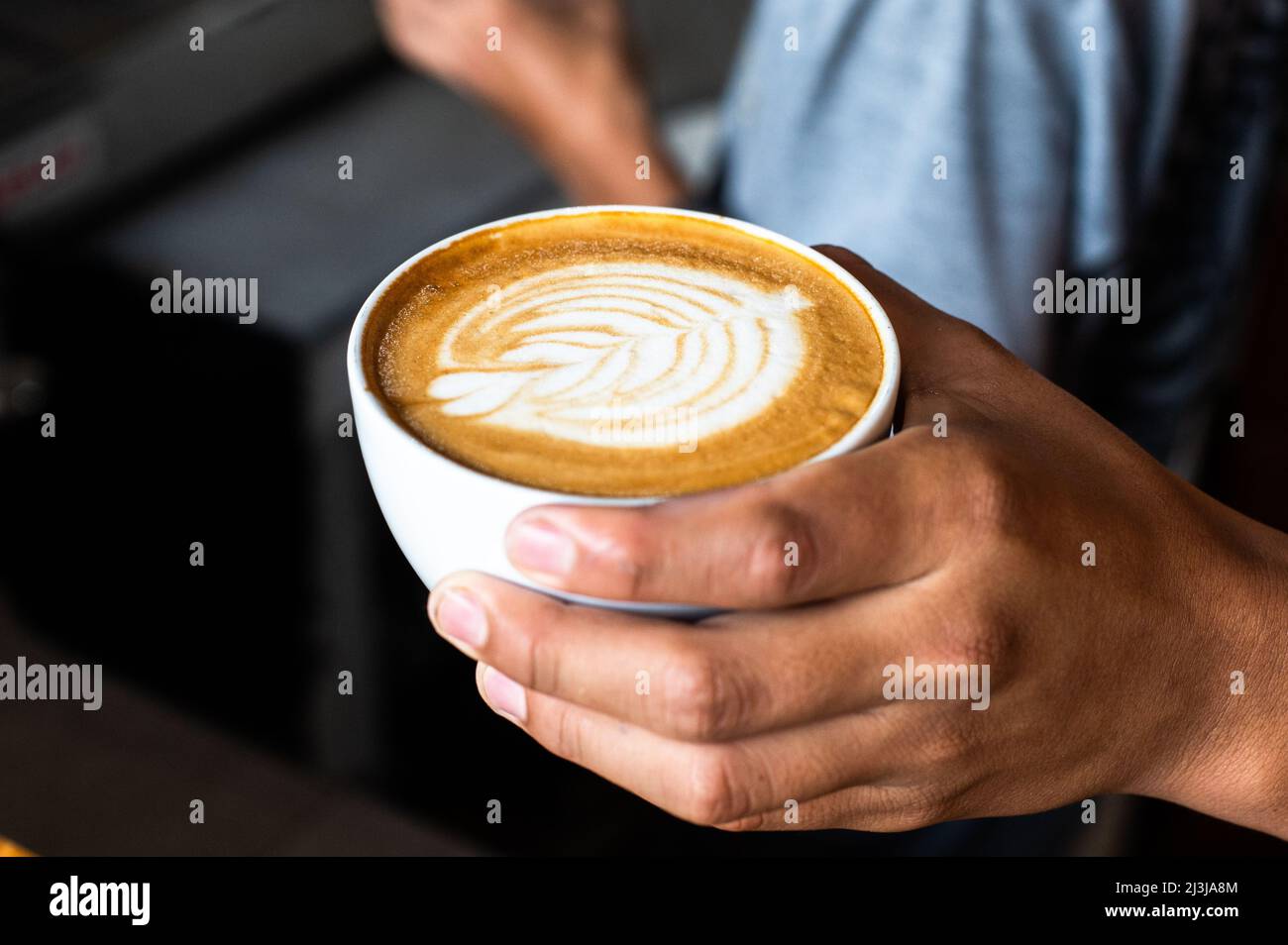 Barista gießt Milch und macht einen Kaffee Latte Art. Menschen gießen Milch zu Latte Art Kaffee im Café oder Café zu machen Stockfoto
