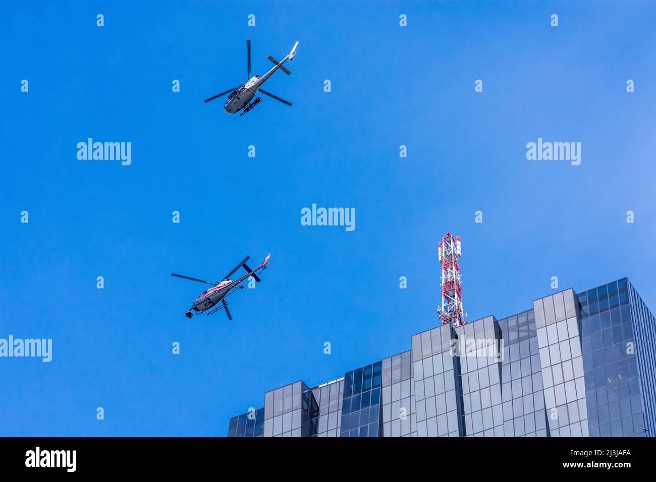 Wien, 2 Helikopter für Dreharbeiten zu Netflix Film 'Tyler Rake ñ Extraction' mit Schauspieler Chris Hemsworth vor dem Wolkenkratzer DC Tower 1, Hubschrauber mit Polizeiaufschrift ist privat und hat eine Kamera im Bezirk 22 davor montiert. Donaustadt, Österreich Stockfoto