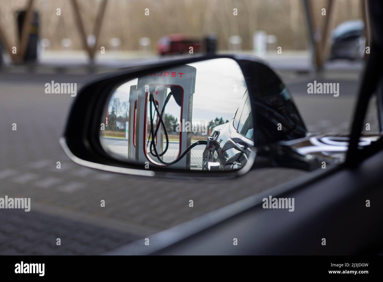 Blick aus dem Auto auf den Seitenspiegel beim Laden an einer elektrischen Ladestation in Deutschland. Stockfoto