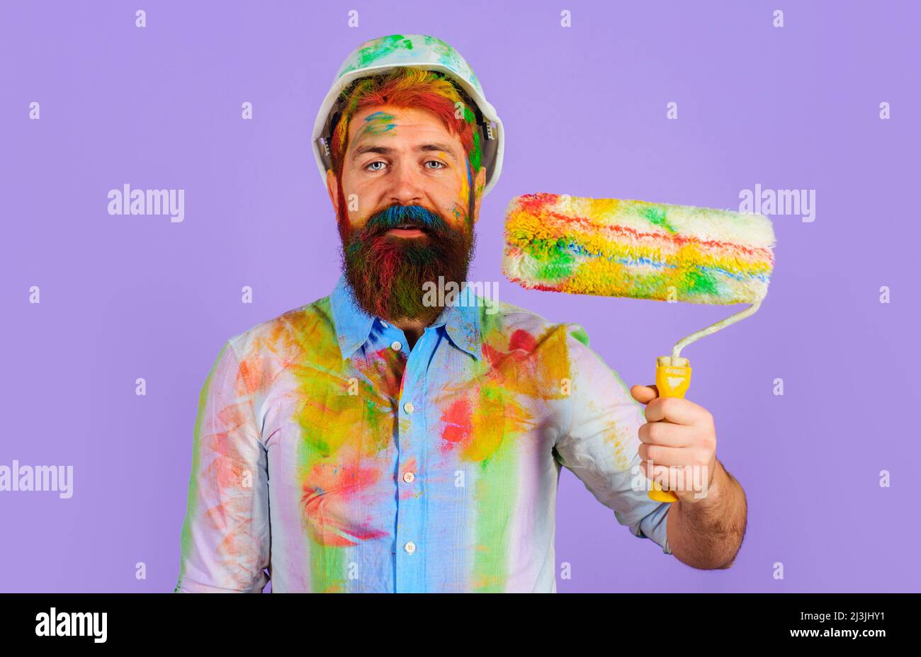 Professioneller Maler im Harthut mit Farbrolle. Builder in Schutzhelm mit Malwerkzeug. Stockfoto