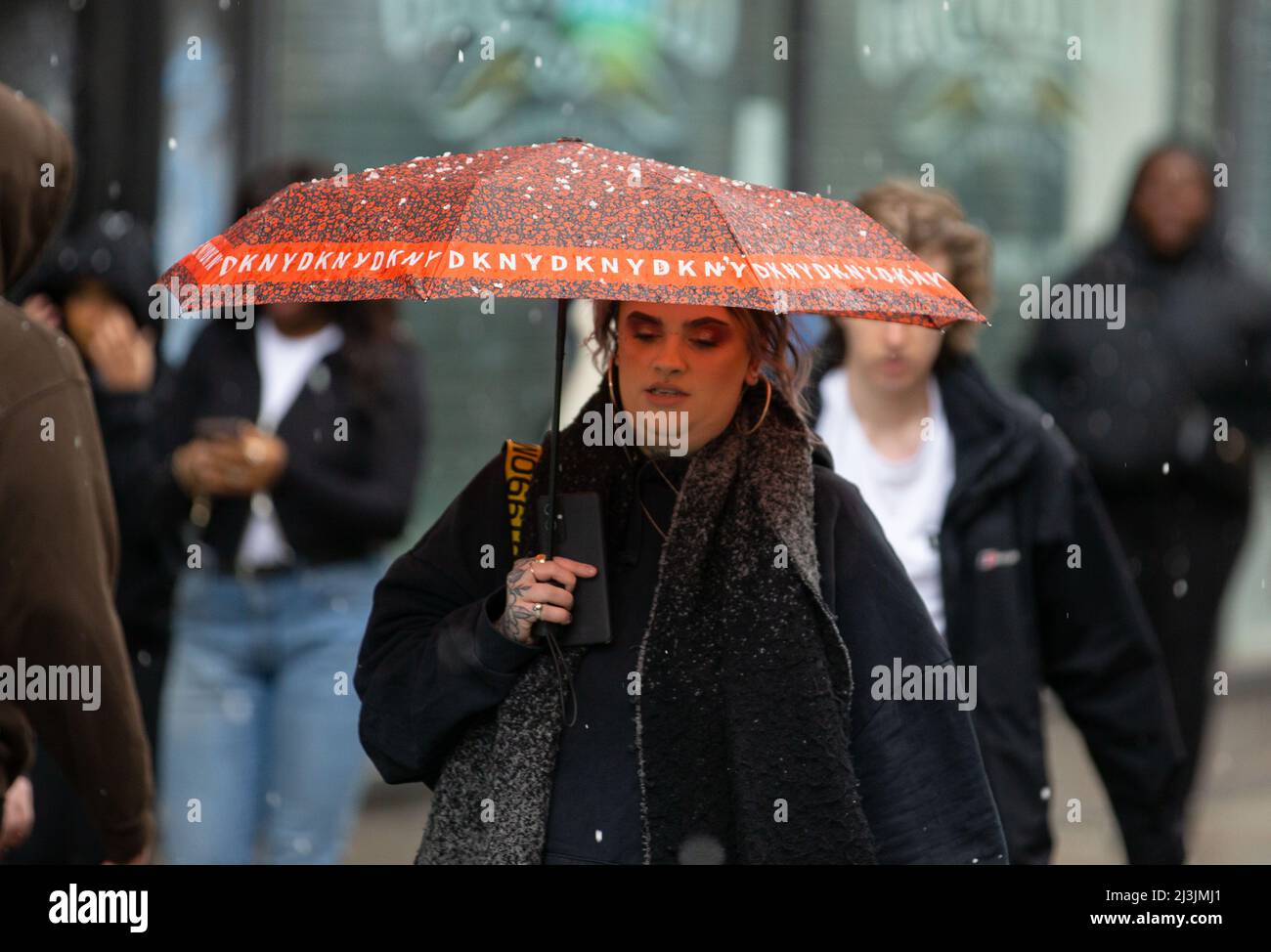 Manchester, Großbritannien. 8. April 2022. Eine Frau, die sich während des Niederschlags unter einem Regenschirm unterm Dach unterbringen kann. Plötzliche Regenfälle überschütteten die Menschen in Manchester City auf der Market Street. Die meisten waren nicht bereit für den plötzlichen Regen, also benutzten sie Sachen wie Mäntel und Schirme, um sich davon abzuhalten nass zu werden. (Bild: © Jake Lindley/SOPA Images via ZUMA Press Wire) Bild: ZUMA Press, Inc./Alamy Live News Stockfoto