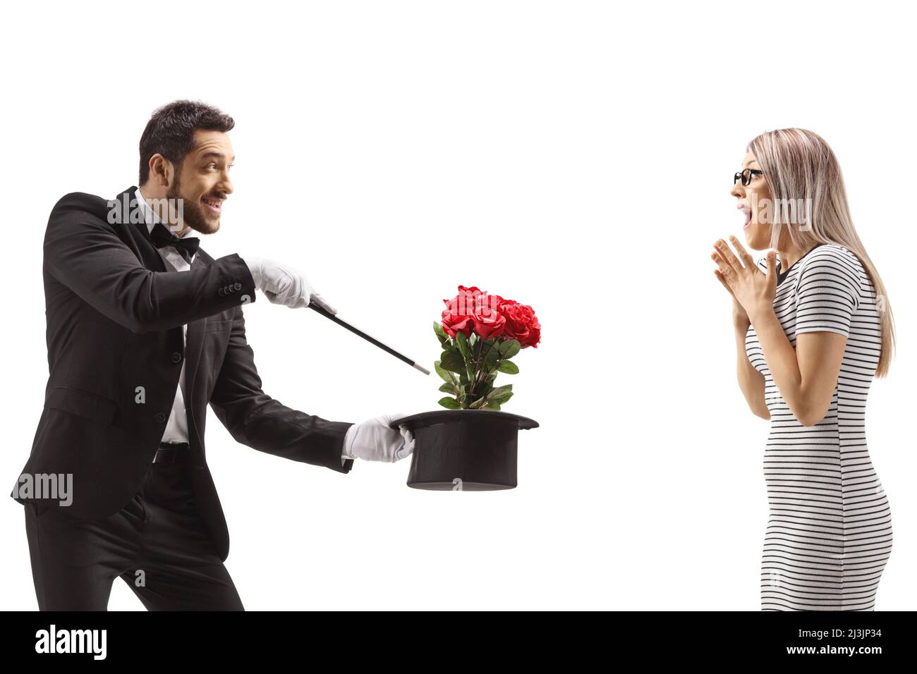 Zauberer macht einen Zaubertrick mit Blumen und einem Hut vor einer überraschten Frau isoliert auf weißem Hintergrund Stockfoto
