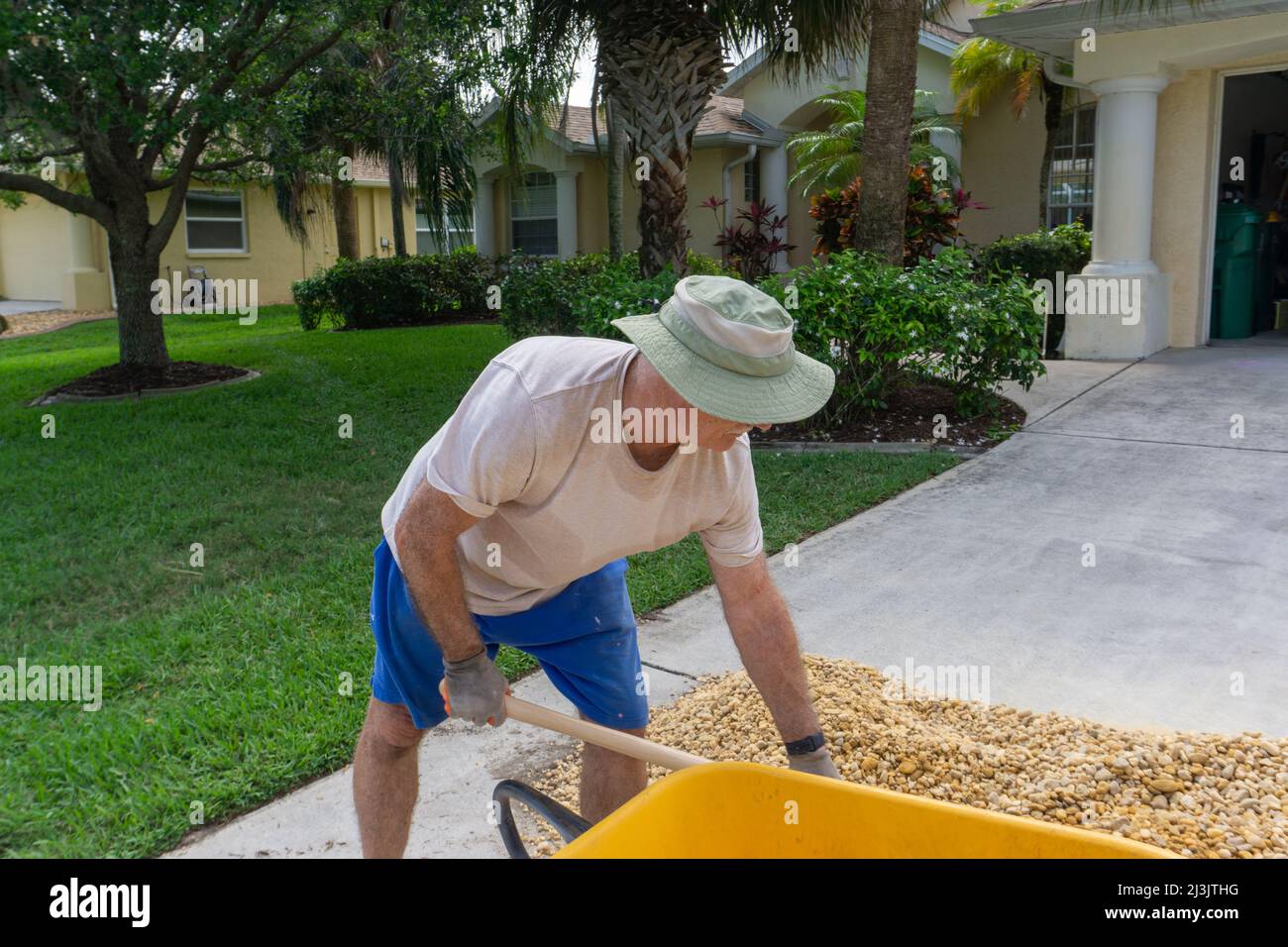 Der alte Mann beugt sich, um in Florida Steine aufzuschaufeln Stockfoto