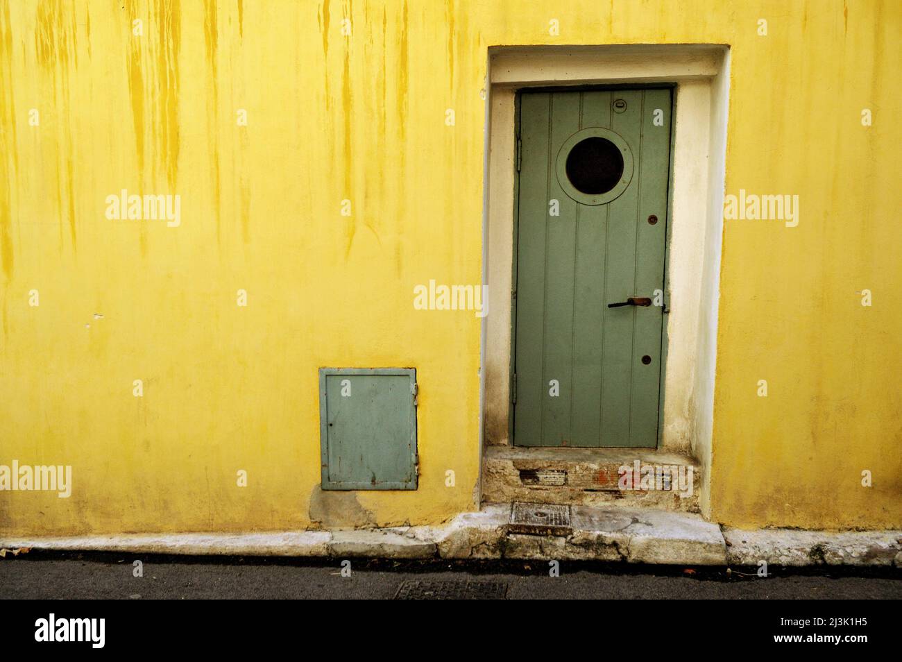 Gelbe Mauer und grüne Tür im Dorf Le Castellet, Var, Provence-Alpes-Côte d'Azur, Frankreich Stockfoto