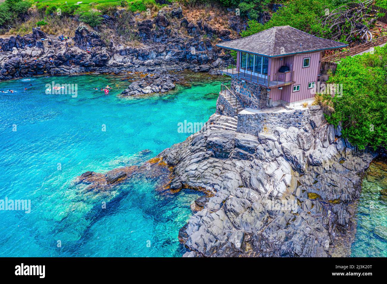 Auf den Klippen an der Küste von Maui, Hawaii, USA, können private Veranstaltungen stattfinden und Schwimmer im Wasser schwimmen Stockfoto