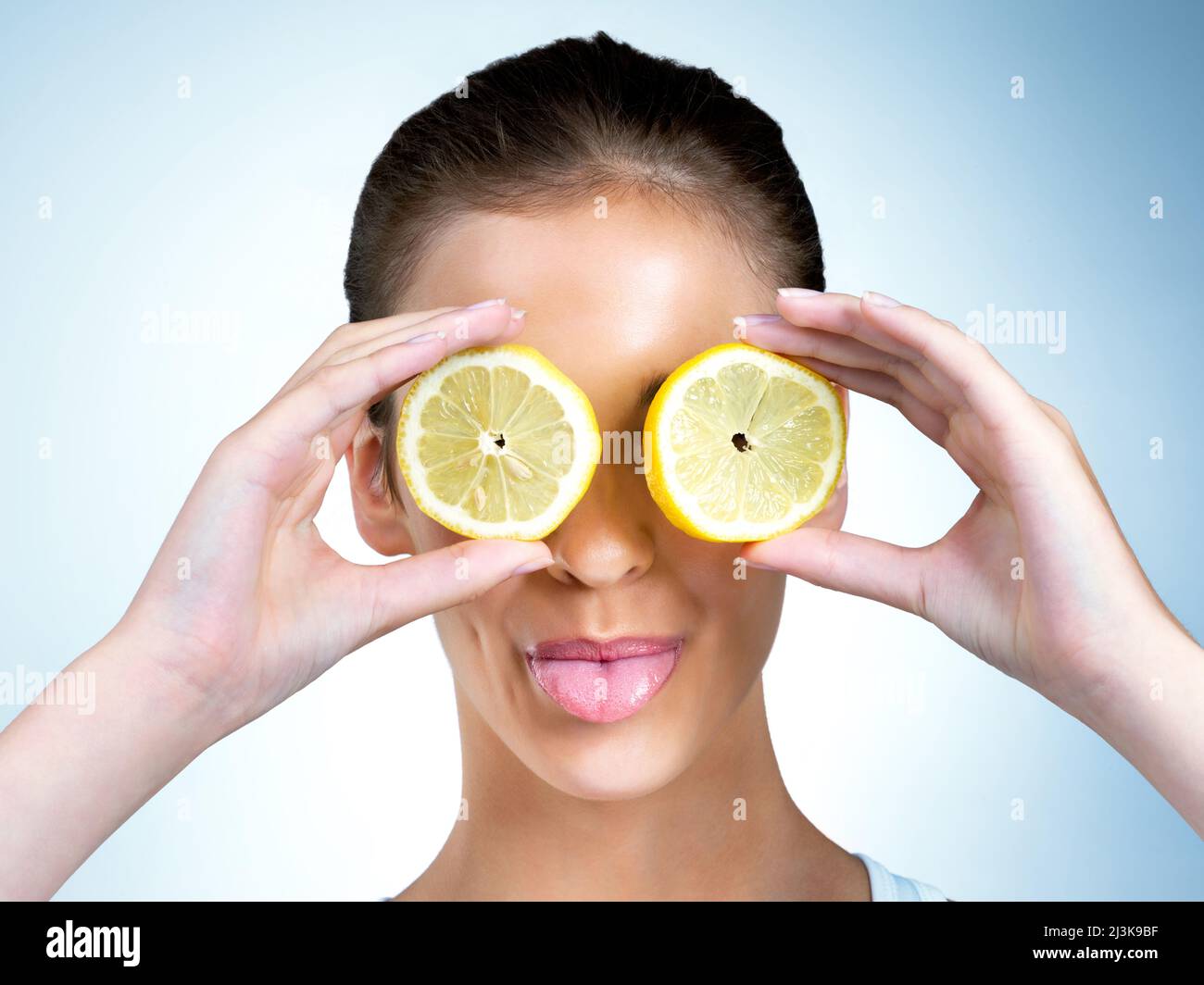 Wenn dir das Leben Zitronen gibt, dann muckert auf. Aufnahme einer gesundheitsbewussten jungen Frau, die im Studio mit Zitronen über ihren Augen posiert. Stockfoto