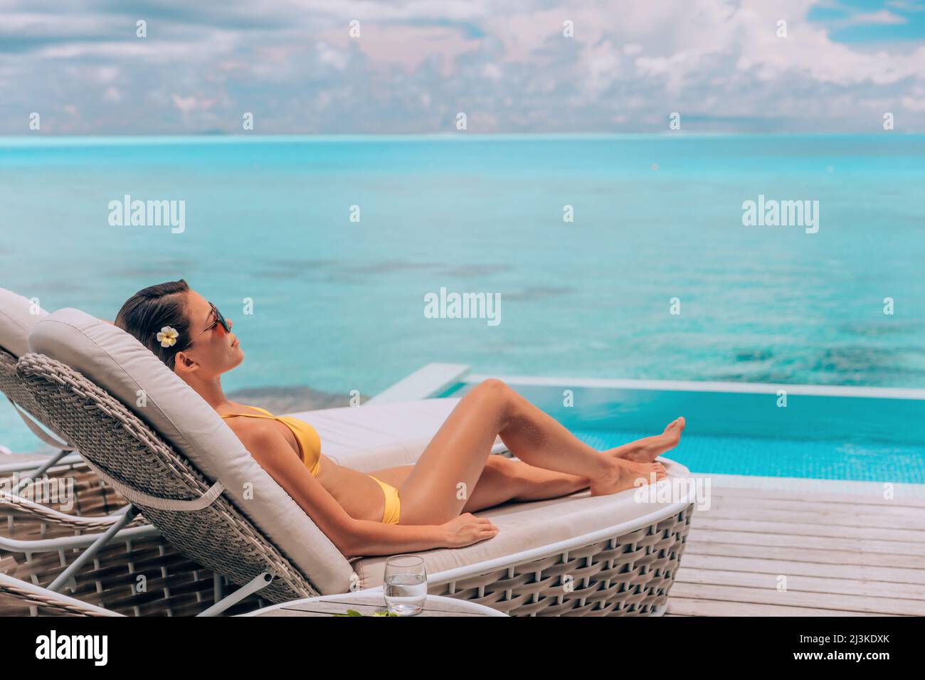 Luxuriöser Urlaub im Paradies Bora Bora High-End Resort Hotel Bikinifrau, die sich entspannt auf einer Liege beim Sonnenbaden am Swimmingpool in der Überwasser-Villa ausruhen kann Stockfoto