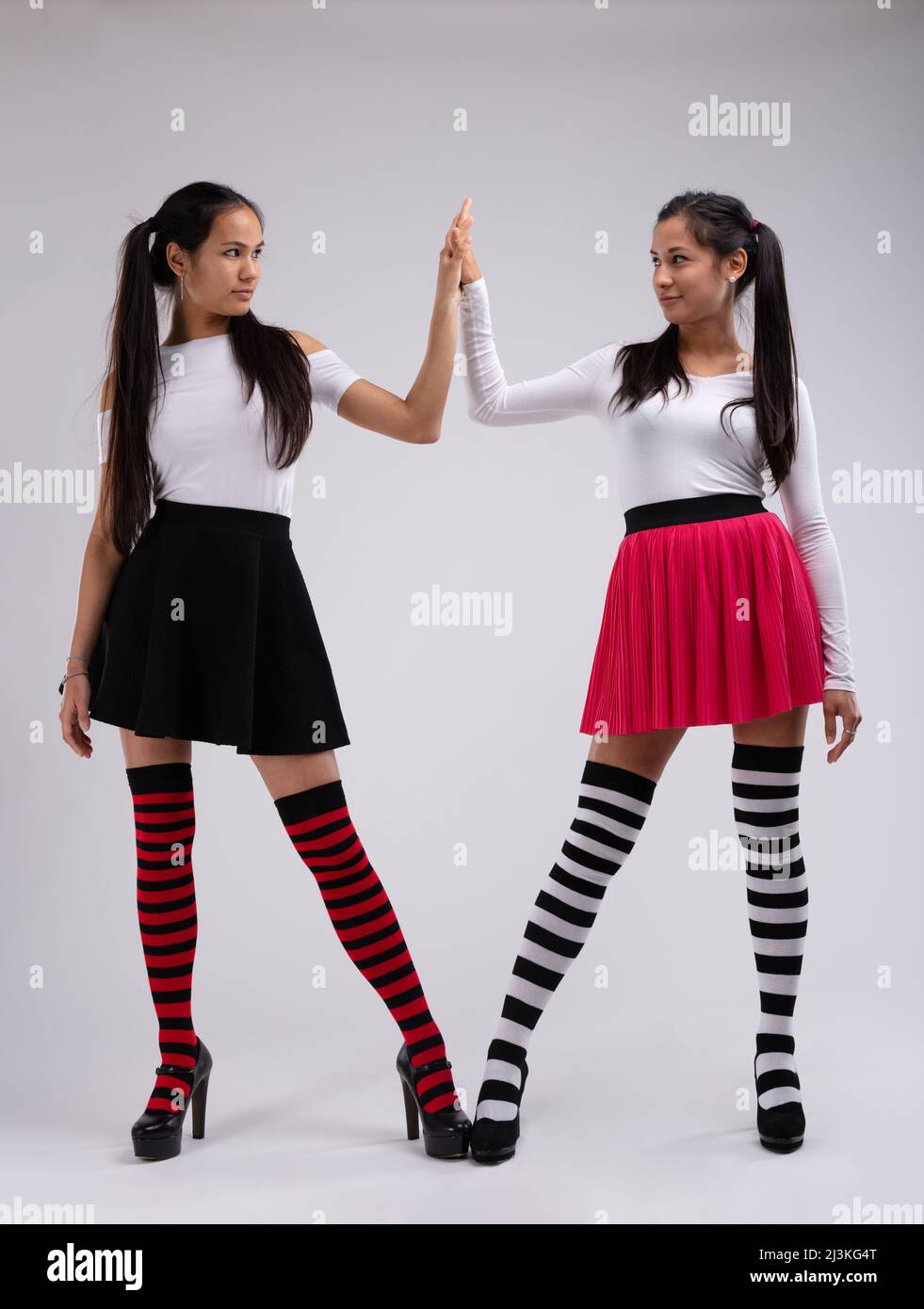 Zwei junge Models im lustigen Outfit, die sich gegenseitig HighFive