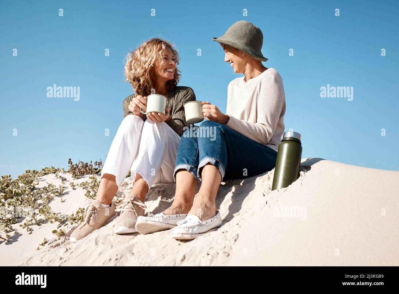 Den Strand zu einem eigenen Café machen. In voller Länge Aufnahme von zwei attraktiven reifen Frauen genießen etwas Kaffee, während am Strand sitzen. Stockfoto