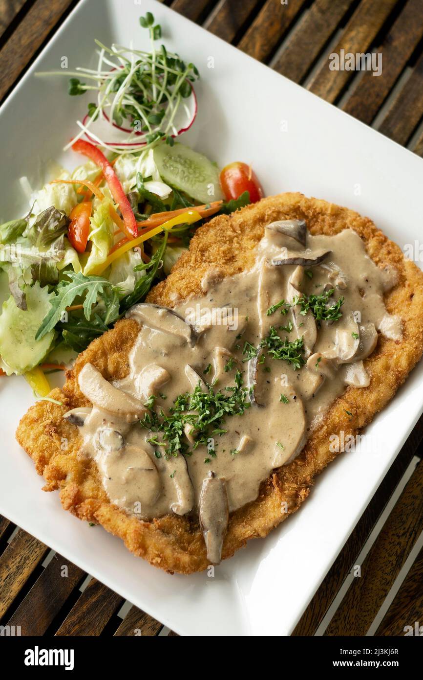 deutsches Kalbfleisch Jagerschnitzel Schnitzel mit Pilzsauce und Salat Stockfoto