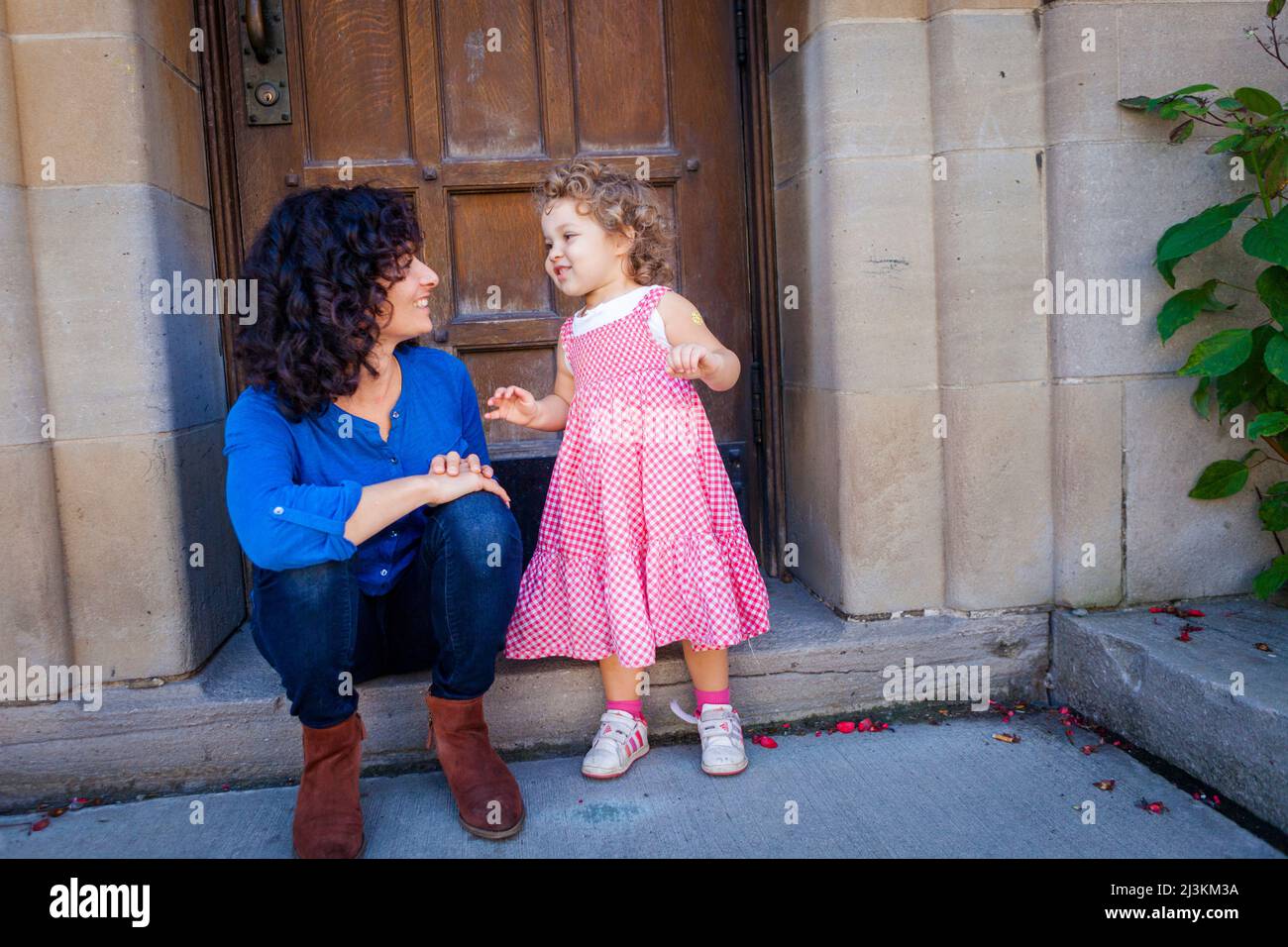 Mutter und junge Tochter sitzen vor der Haustür und unterhalten sich miteinander; Toronto, Ontario, Kanada Stockfoto