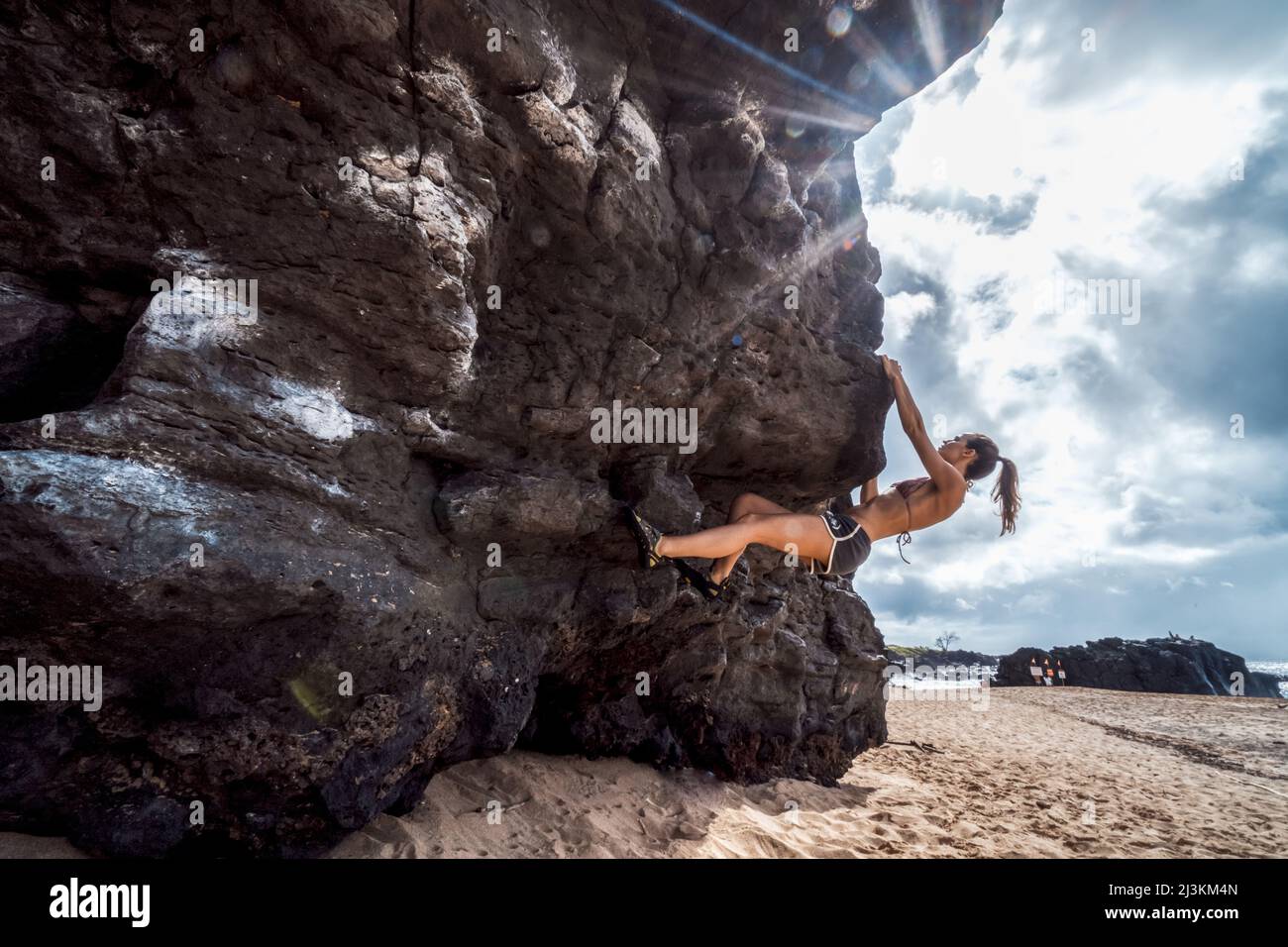 Eine Frau Bouldern am Strand von Hawaii. Stockfoto