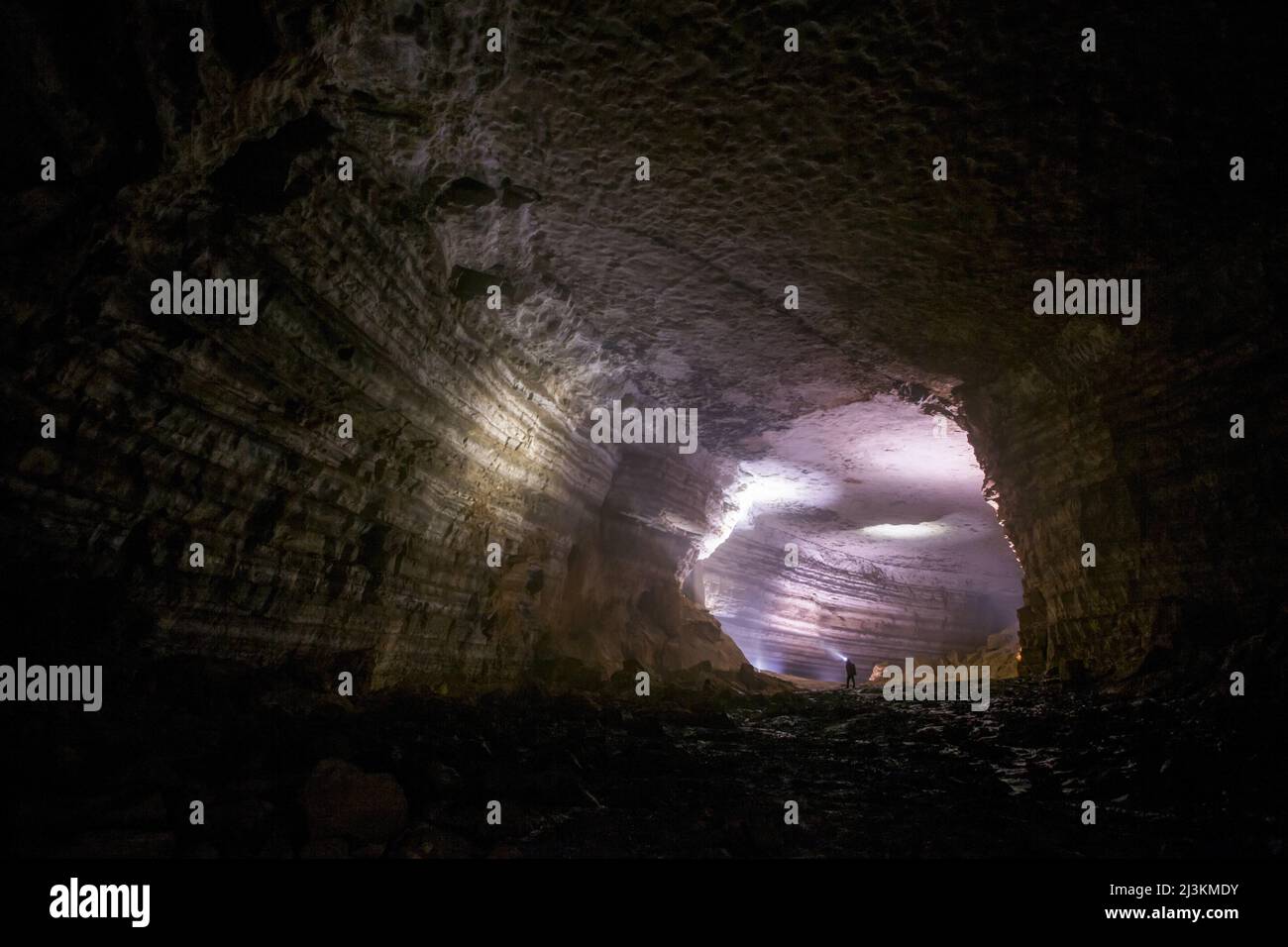 Ein Mann scheint seine Scheinwerfer auf die komplizierten Strukturen auf die Wände der Höhle in China. Stockfoto